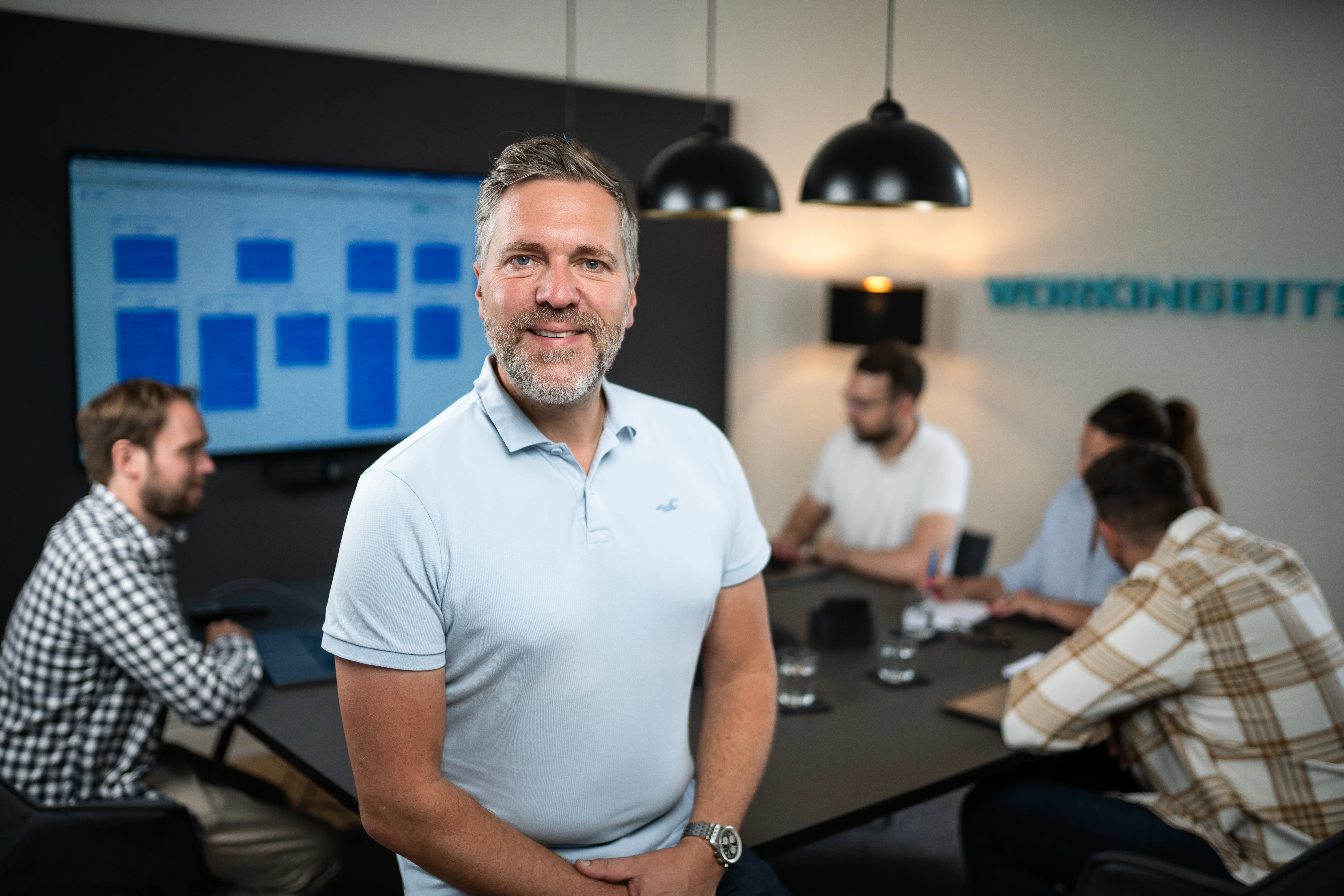 Andreas Otto von workingbits, im Hintergrund das Team bei einer Besprechung im Büro